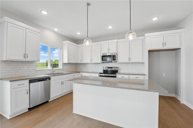 780 Creekmoor Dr, Raymore, MO 64083 - kitchen featuring appliances with stainless steel finishes, a sink, a center island, white cabinetry, and light wood-style flooring