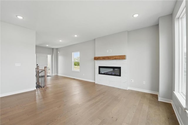 780 Creekmoor Dr, Raymore, MO 64083 - unfurnished living room with wood finished floors, a glass covered fireplace, recessed lighting, and baseboards