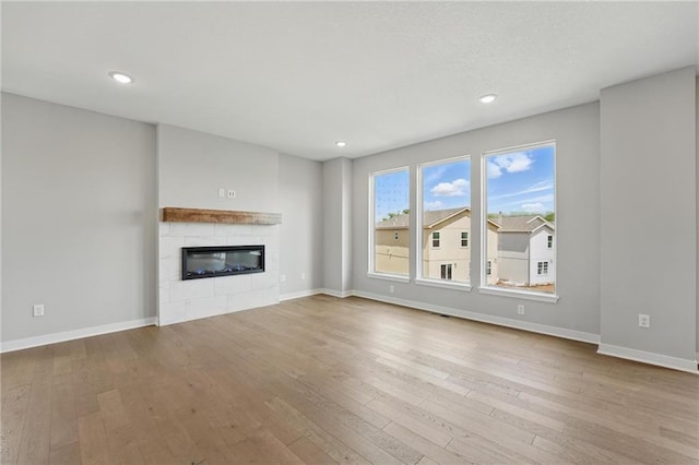 780 Creekmoor Dr, Raymore, MO 64083 - unfurnished living room featuring hardwood / wood-style floors, a glass covered fireplace, baseboards, and recessed lighting