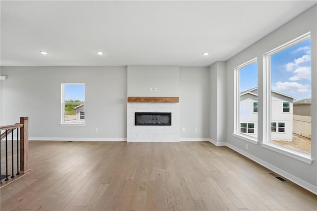 780 Creekmoor Dr, Raymore, MO 64083 - unfurnished living room with healthy amount of natural light, wood finished floors, a glass covered fireplace, baseboards, and recessed lighting