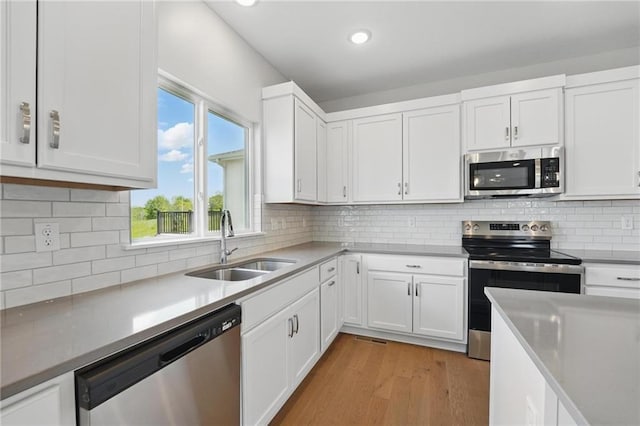 780 Creekmoor Dr, Raymore, MO 64083 - kitchen featuring appliances with stainless steel finishes, a sink, white cabinetry, light wood-style floors, and recessed lighting