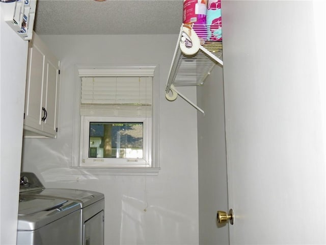 washroom featuring cabinets, a textured ceiling, and washing machine and dryer