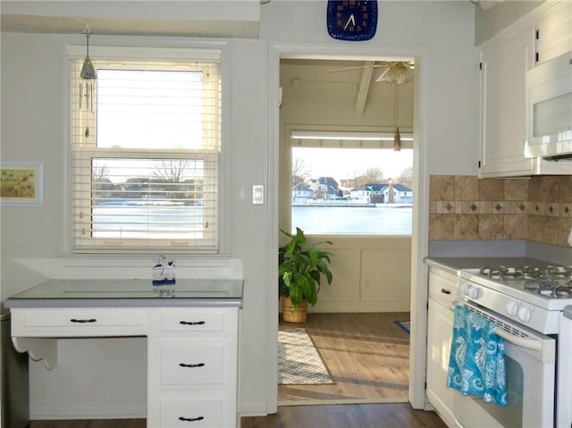 kitchen featuring white appliances, dark wood-type flooring, white cabinetry, decorative backsplash, and hanging light fixtures