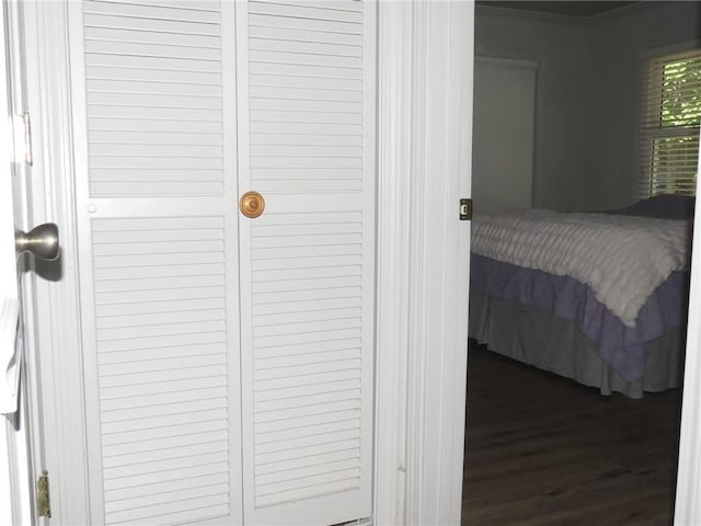 bedroom featuring a closet, hardwood / wood-style flooring, and crown molding