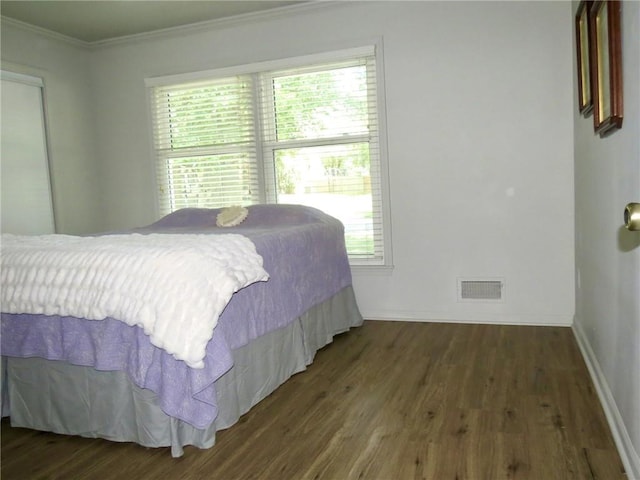 bedroom featuring crown molding and dark wood-type flooring