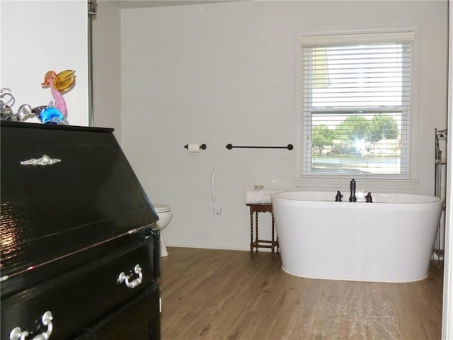 bathroom with hardwood / wood-style floors, toilet, and a bathtub