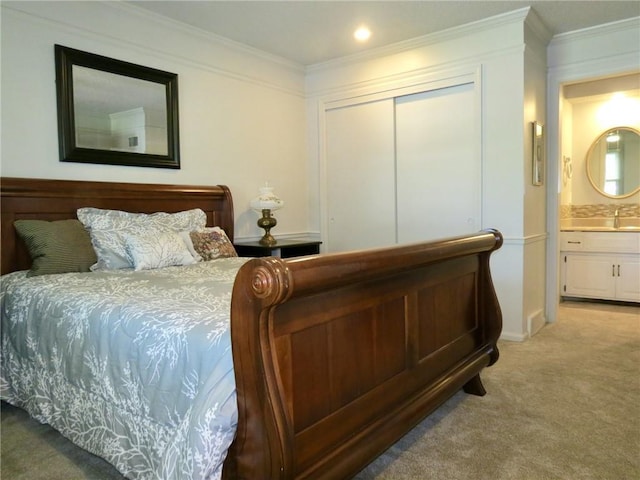 bedroom featuring ensuite bathroom, a closet, sink, carpet, and ornamental molding