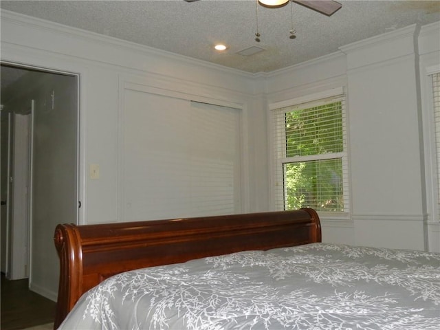 bedroom featuring a closet, ceiling fan, ornamental molding, and a textured ceiling