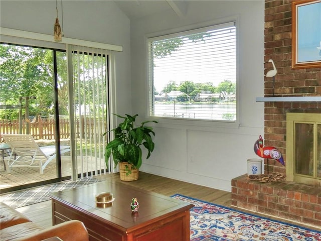1005 Johnston Dr, Raymore, MO 64083 - living area featuring wood finished floors, a brick fireplace, and lofted ceiling