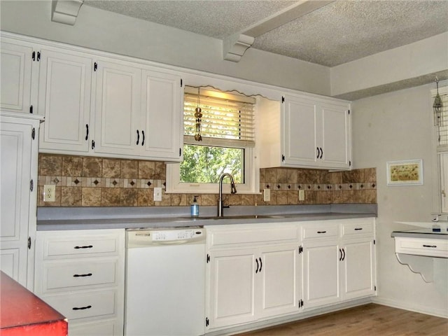 1005 Johnston Dr, Raymore, MO 64083 - kitchen featuring white dishwasher, tasteful backsplash, white cabinets, a textured ceiling, and light wood-type flooring