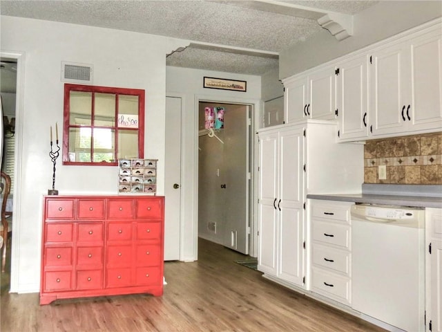 1005 Johnston Dr, Raymore, MO 64083 - kitchen featuring dishwasher, light wood-style flooring, a textured ceiling, decorative backsplash, and white cabinetry