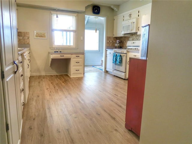 1005 Johnston Dr, Raymore, MO 64083 - kitchen with white appliances, light wood-type flooring, white cabinets, tasteful backsplash, and baseboards