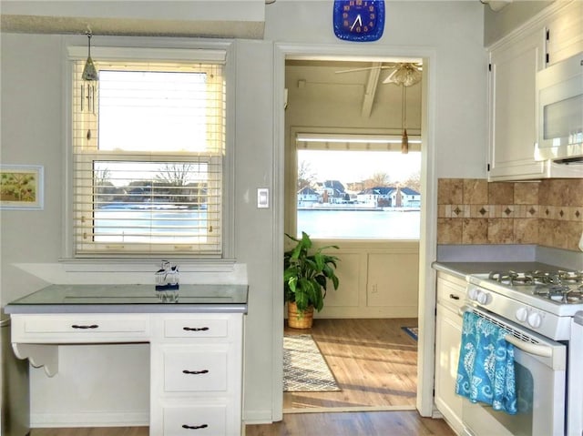 1005 Johnston Dr, Raymore, MO 64083 - kitchen with white appliances, white cabinetry, healthy amount of natural light, and wood finished floors