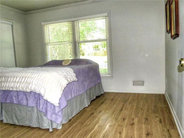 1005 Johnston Dr, Raymore, MO 64083 - bedroom with multiple windows, crown molding, wood finished floors, and baseboards