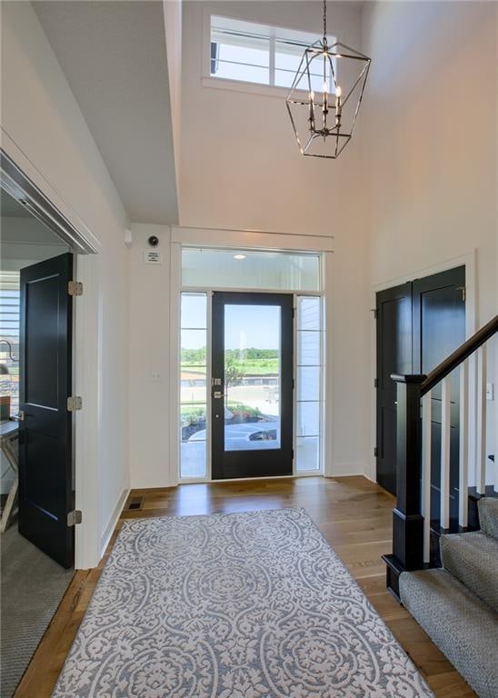 foyer entrance featuring light hardwood / wood-style floors, an inviting chandelier, and a towering ceiling