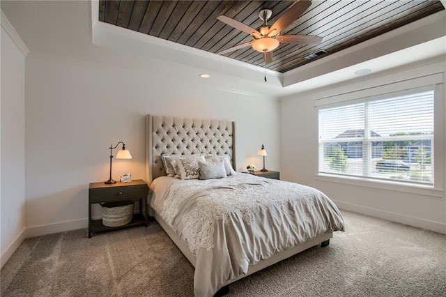 carpeted bedroom featuring crown molding, wood ceiling, a tray ceiling, and ceiling fan