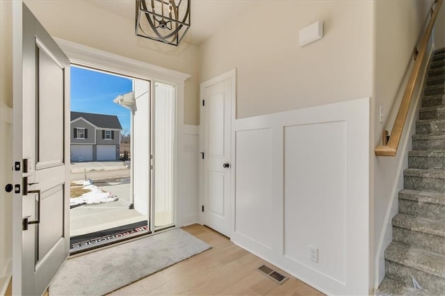 doorway featuring light wood finished floors, visible vents, and stairway