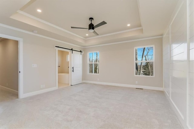 unfurnished bedroom featuring a barn door, multiple windows, and a raised ceiling