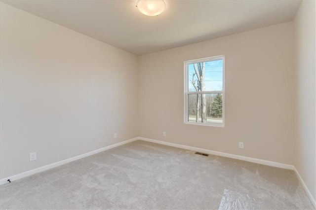 empty room with baseboards, visible vents, and light colored carpet