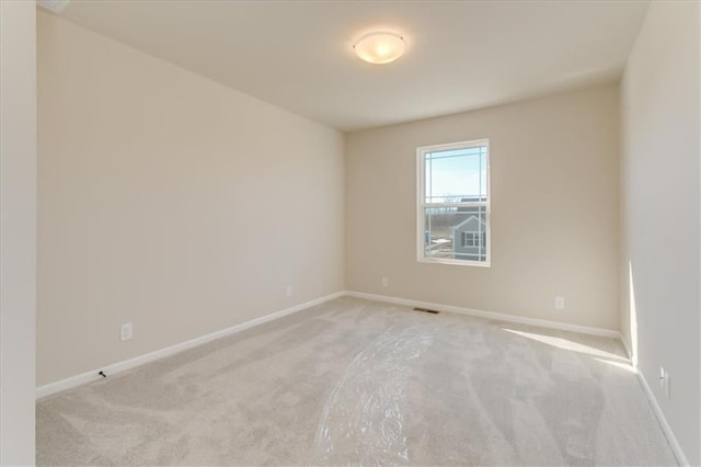 unfurnished room with baseboards, visible vents, and light colored carpet