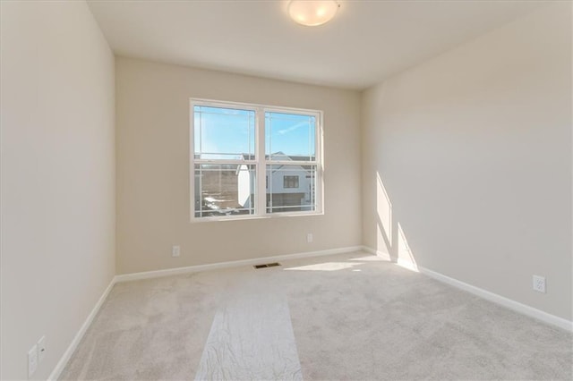 spare room featuring carpet, visible vents, and baseboards