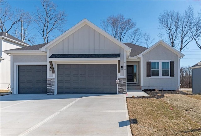 view of front of house featuring a garage, a shingled roof, concrete driveway, stone siding, and board and batten siding