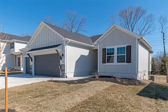 view of front of house featuring roof with shingles, an attached garage, stone siding, driveway, and a front lawn