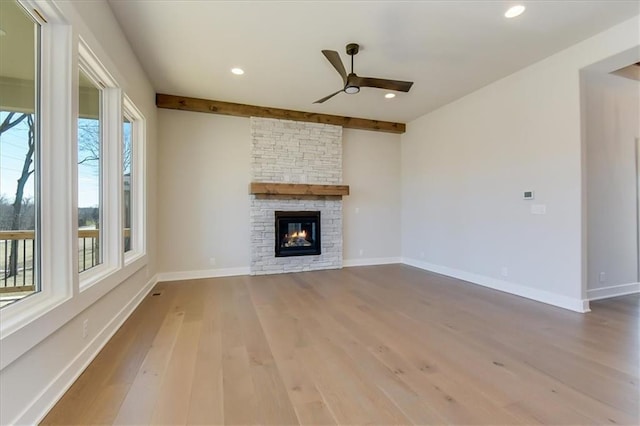 unfurnished living room featuring recessed lighting, ceiling fan, a stone fireplace, wood finished floors, and baseboards