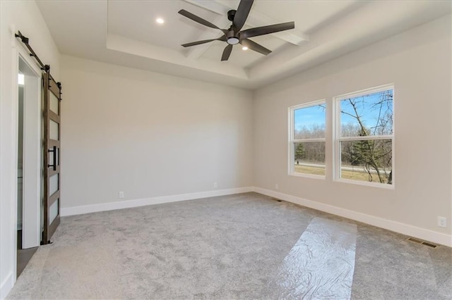 empty room with recessed lighting, visible vents, a barn door, carpet flooring, and baseboards