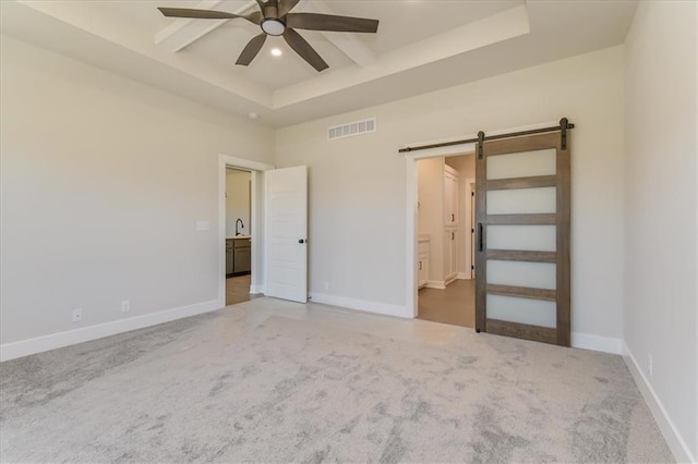 unfurnished bedroom featuring a barn door, visible vents, coffered ceiling, carpet flooring, and beam ceiling