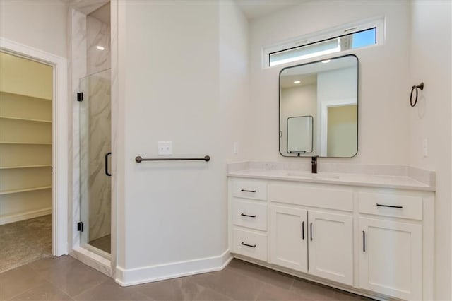 bathroom featuring tile patterned floors, a marble finish shower, vanity, and baseboards