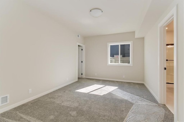 spare room with carpet floors, visible vents, and baseboards