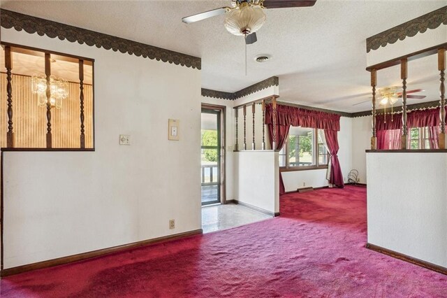 spare room with carpet flooring, ceiling fan with notable chandelier, and a textured ceiling