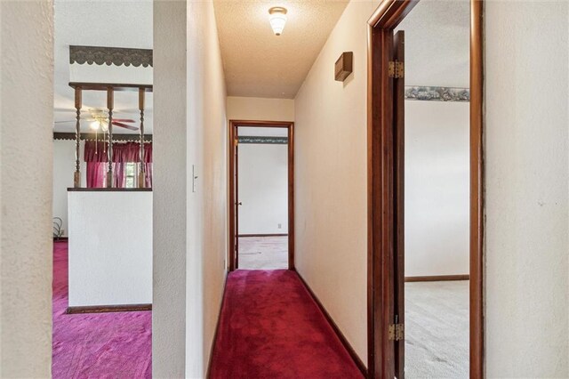 hallway with a textured ceiling and carpet floors