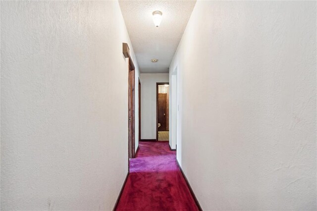 hall with a textured ceiling and carpet floors