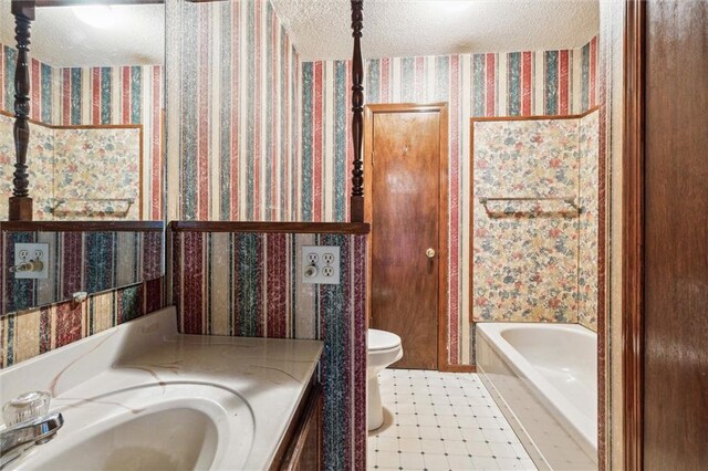 bathroom with a tub to relax in, toilet, vanity, and a textured ceiling