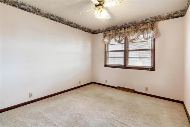 spare room featuring light colored carpet and ceiling fan