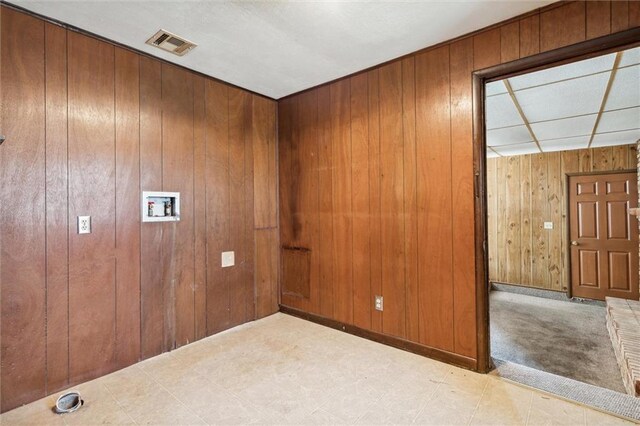 spare room with wooden walls and a drop ceiling