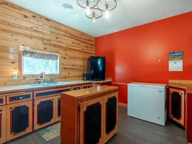 kitchen featuring wood walls, dark hardwood / wood-style floors, sink, and refrigerator