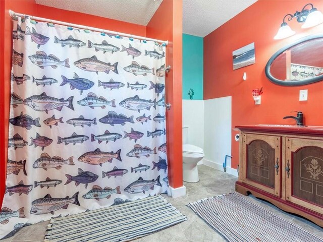 bathroom featuring toilet, a textured ceiling, tile patterned flooring, and vanity