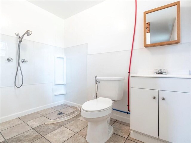 bathroom featuring tile patterned flooring, vanity, walk in shower, and toilet