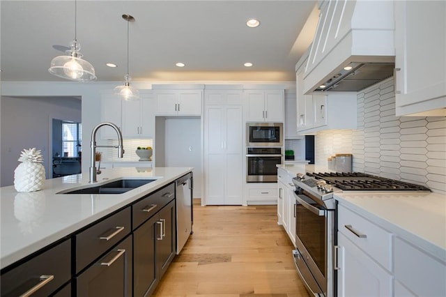 kitchen with custom exhaust hood, white cabinetry, appliances with stainless steel finishes, and sink