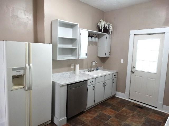 kitchen featuring dark tile patterned floors, dishwasher, sink, and white refrigerator with ice dispenser