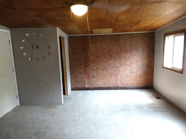 carpeted empty room featuring wooden ceiling