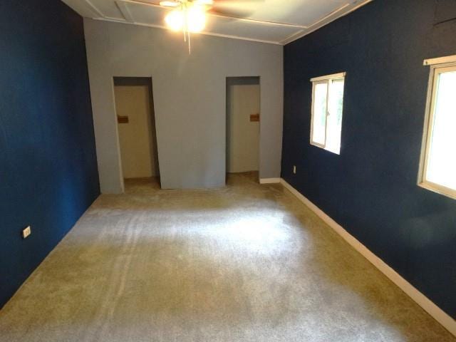 unfurnished bedroom with light colored carpet, vaulted ceiling, and ceiling fan