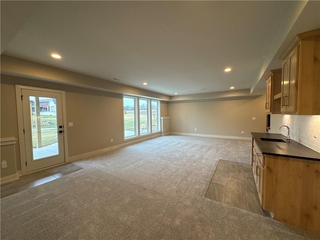 kitchen featuring sink, light colored carpet, light brown cabinetry, and decorative backsplash