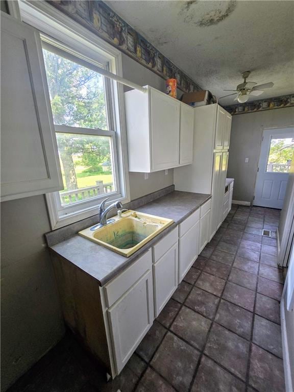 kitchen with white cabinets, tile patterned floors, a wealth of natural light, and ceiling fan