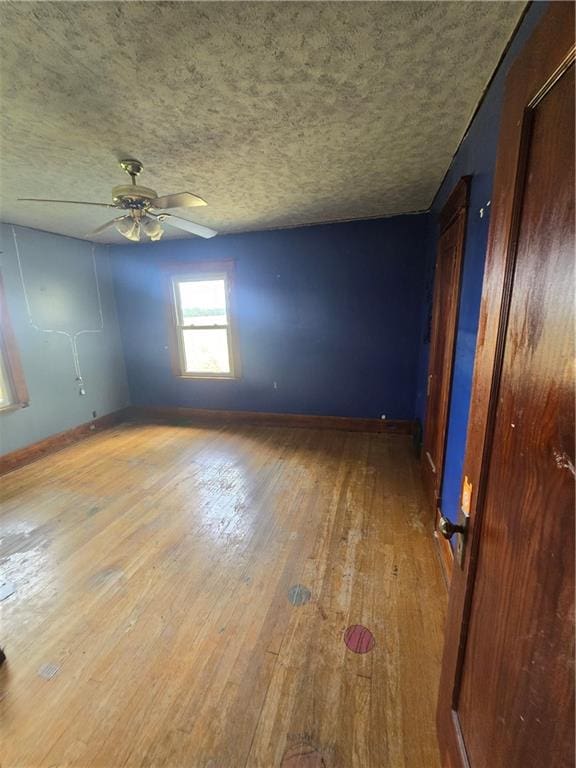 empty room with a textured ceiling, wood-type flooring, and ceiling fan