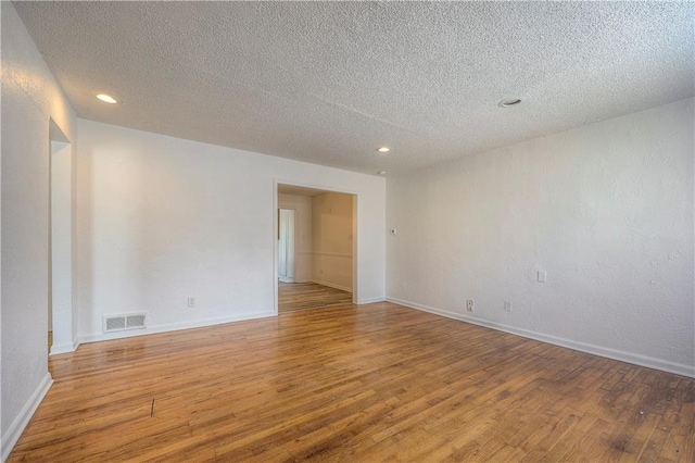 spare room featuring light hardwood / wood-style flooring and a textured ceiling