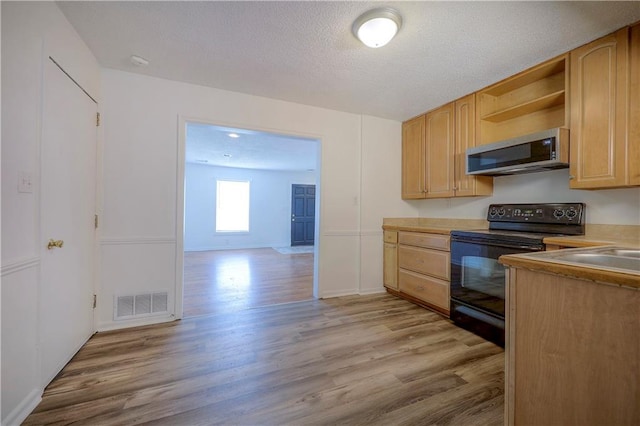 kitchen featuring light brown cabinets, light wood-type flooring, a textured ceiling, and black range with electric cooktop